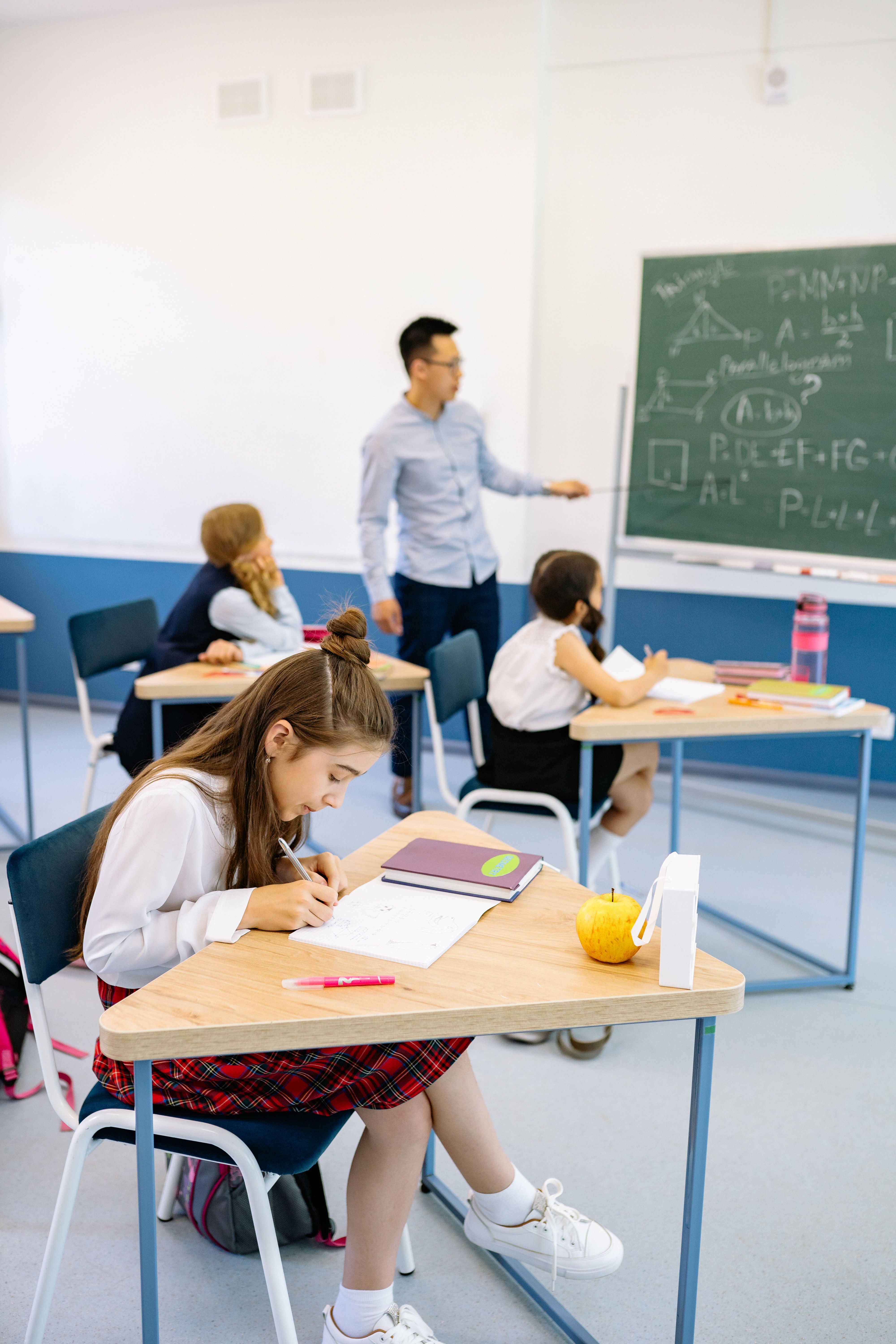 Primary school pupils at desks with teacher at board